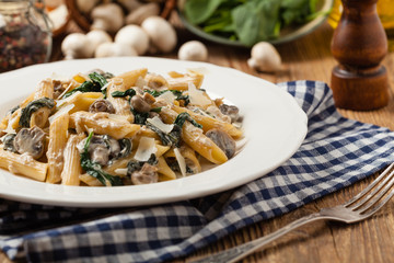 Penne pasta with spinach and mushrooms. Sprinkled with cheese.