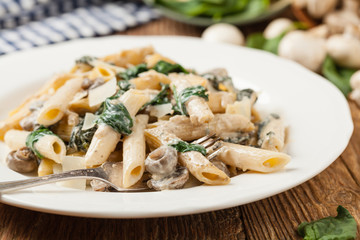 Penne pasta with spinach and mushrooms. Sprinkled with cheese.