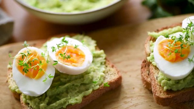 Breakfast toast with egg and avocado on breakfast table. Closeup view. HD footage