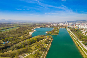 Zagreb, Croatia, Jarun lake, beautiful green recreation park area, sunny spring day, panoramic view from drone, city in background