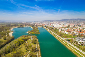 Obraz premium Zagreb, Croatia, Jarun lake, beautiful green recreation park area, sunny spring day, panoramic view from drone, city in background