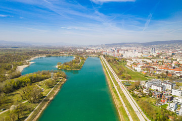 Obraz premium Zagreb, Croatia, Jarun lake, beautiful green recreation park area, sunny spring day, panoramic view from drone, city in background