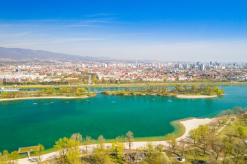 Zagreb, Croatia, Jarun lake, beautiful green recreation park area, sunny spring day, panoramic view from drone, city in background