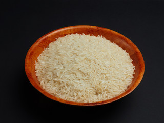 White basmati rice in a bamboo bowl on a black background