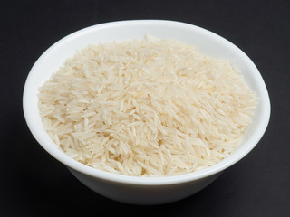 White basmati rice in a white bowl on a black background