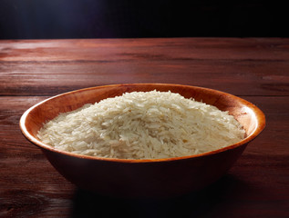 Fototapeta na wymiar White basmati rice in a bamboo bowl on a brown wooden background