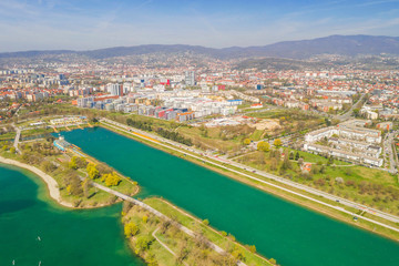 Obraz premium Zagreb, Croatia, Jarun lake, beautiful green recreation park area, sunny spring day, panoramic view from drone, city in background