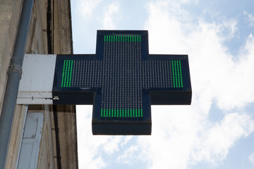Pharmacy green cross sign in street shop