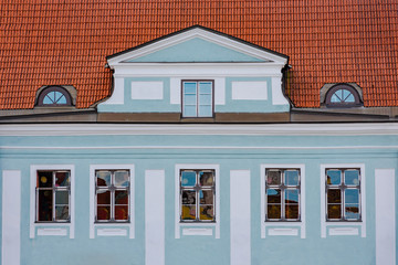 Obraz premium Facade of blue building with windows and red tile roof