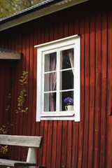 Fototapeta na wymiar A window on the wall of a red wooden house in Sweden.