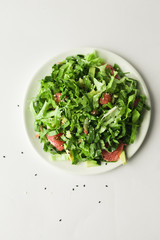 Healthy green vegan salad with grapfruit in white plate