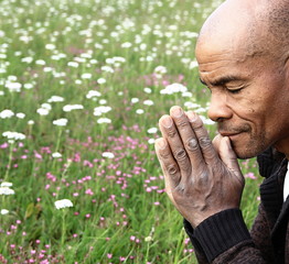 Caribbean man praying to god with hands together stock photo