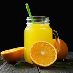 Fresh cold orange juice on dark wooden background