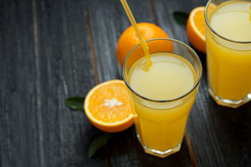 Fresh cold orange juice on wooden dark background with copyspace