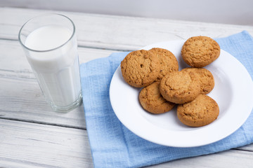 Glass of milk and cookies on a wooden white table