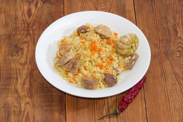 Cooked pilaf on white dish on rustic table close-up