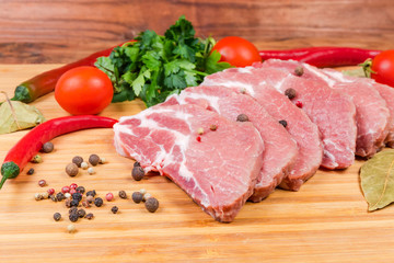 Fototapeta premium Uncooked steaks of pork neck on cutting board close-up