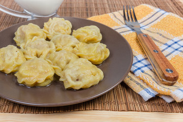Cooked homemade meat dumplings and fork on bamboo table mat