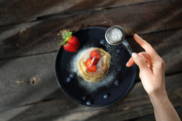Homemade pancakes with strawberries, blueberries and powdered sugar. Sweet breakfast.