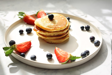 Homemade pancakes with strawberries, blueberries and maple syrup. Sweet breakfast.