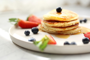 Homemade pancakes with strawberries, blueberries and maple syrup. Sweet breakfast.