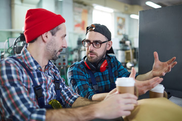 Portrait of two factory workers chatting during coffee break in workshop, copy space
