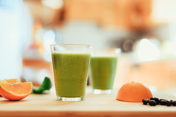 Good morning: Fresh green smoothies and fruits in the kitchen, healthy breakfast