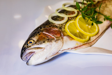 Fish on a plate with onions and lemon. Trout with onion rings and lemon.