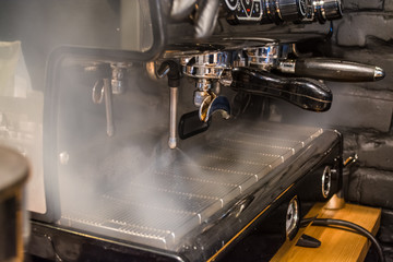 Work the barista in coffee shop on the coffee machine. The steamer is on. Hot steam. Processing....