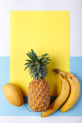 Tropical fruits on colorful background. Pineapple, mango, banana. Healthy food background. Summer concept. Top view, copy space, flat lay.
