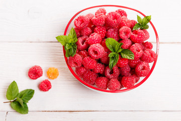 Ripe sweet raspberries in bowl on wooden table. Close up, top view, high resolution product