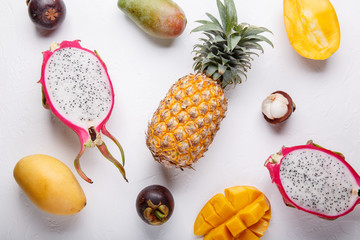 Tropical fruits on white. Dragon fruit, mango, pineapple, mangosteen, banana, coconut. Healthy food background. Summer concept. Top view, copy space, flat lay.