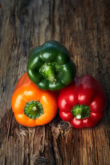 Colorful green, yellow, and red peppers paprika on wooden background