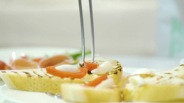 Work of a professional chef for the preparation of traditional canapes. Process of preparation toasts with cheese, tomato and becon on the plate in the restaurant.