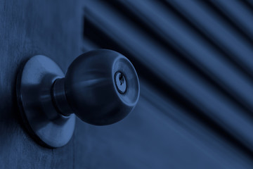 security concept of stainless door knob and keyhole on old wooden door at night, shallow depth of field