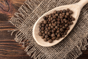 Black pepper on dark wooden background. 