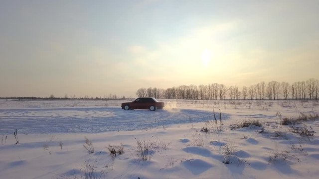 Red retro car drift on a field in the snow