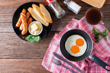 Breakfast with fried eggs on pan and sausage grill with toast, coffee on table, Healthy homemade meal. Top view and Copy space.