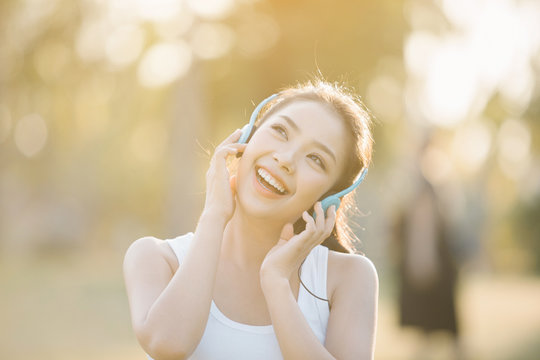 Beautiful Asian Woman Listening Music In The Park