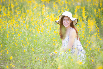 happy young woman enjoying summer in yellow flower field