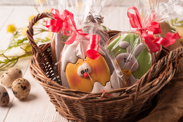 Fototapeta na wymiar brown basket with wrapped easter cookies near quail eggs and blossoming branch on wooden surface