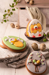 easter cookies with painted easter bunny and chicken in bowl near quail eggs, decorative sideboard and napkin on wooden surface
