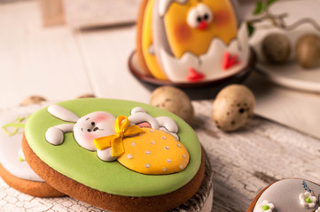 Obraz premium selective focus of easter green cookie with painted easter bunny in white bow holding strawberry on white cutting boards and wooden surface