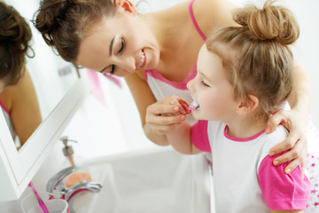 Woman and child brush their teeth 