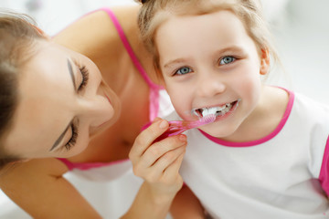 Woman and child brush their teeth 