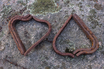Old rusty railway spikes arranges to look like hearts on a rock with lichen