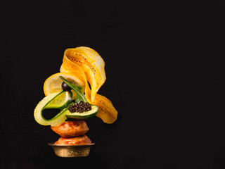 Elegant tasty snack with black caviar,  banana chips and fresh young cucumber.