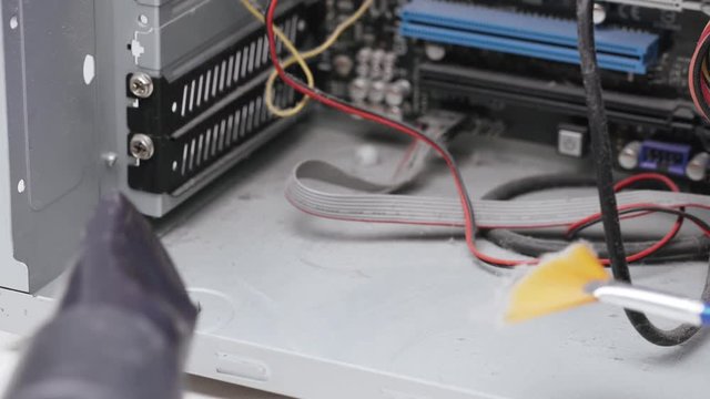 Service for repair and cleaning of computer equipment. The service worker removes dust and dirt from inside the PC case with a brush and vacuum cleaner.
