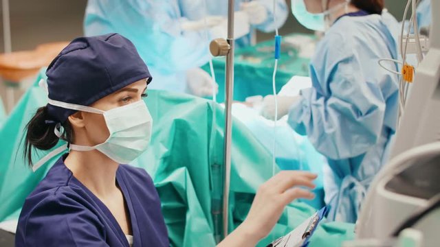 Young anesthesiologist writing down all the parameters on form 