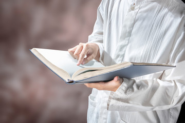 Muslim man standing while reading the quran on his hands